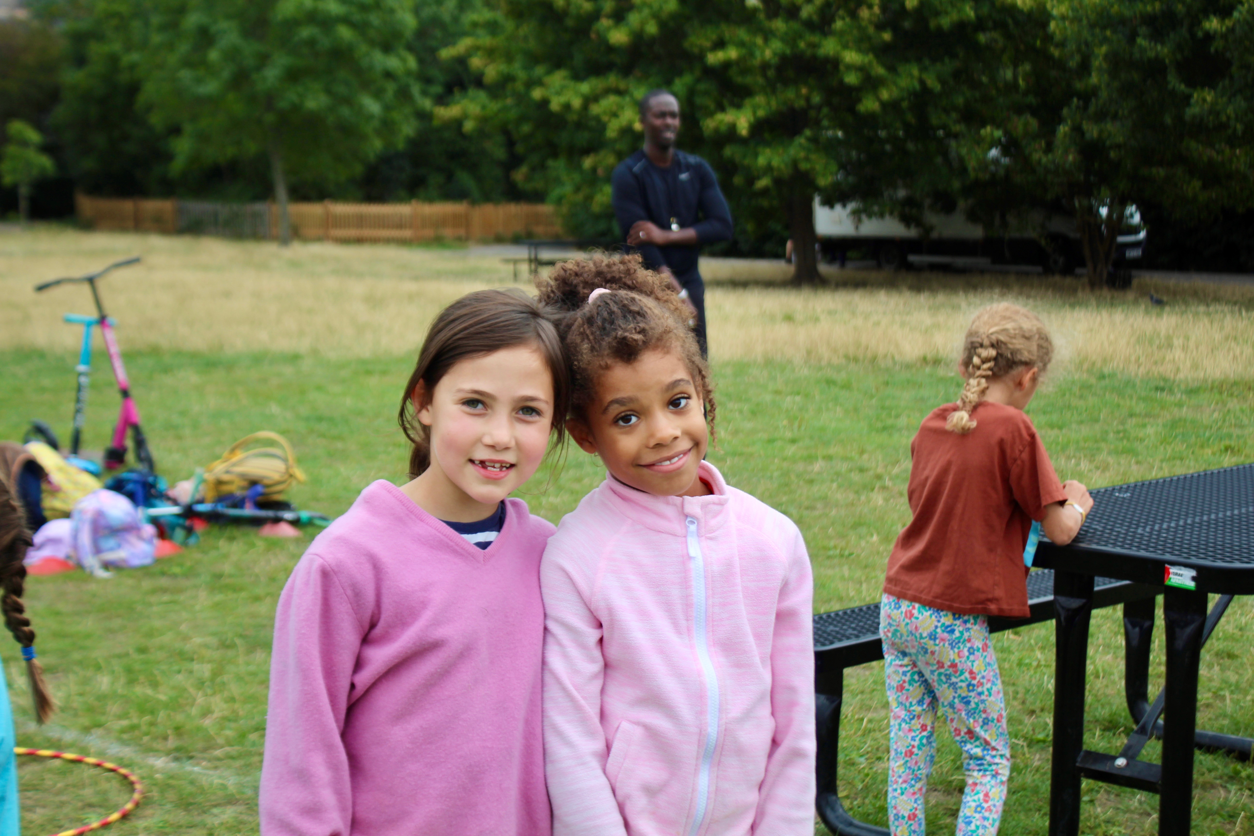 Photo of two little girls dressed in pink and smiling at the camera